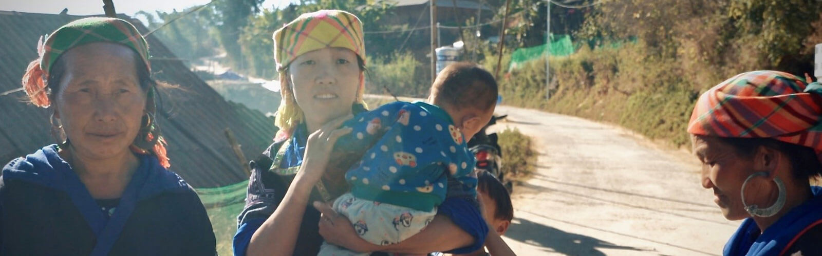 A woman carrying a toddler with two women in the background