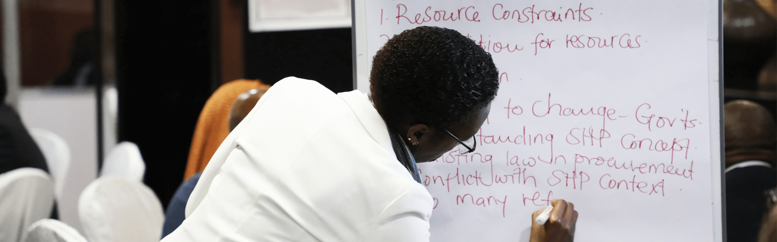 Woman writing on flipchart at the Strategic Purchasing Africa Resource Center (SPARC) convening of policymakers from 12 countries for 3 days in Arusha, Tanzania July 2022