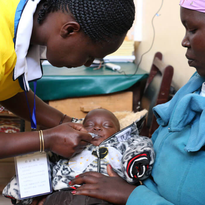 A baby being given an oral vaccine by a health worker
